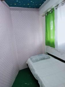 Habitación pequeña con cama y cortina verde en Quickshape/Quickshield Homestay en Naga