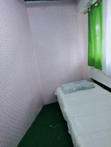 Habitación pequeña con cama y cortina verde en Quickshape/Quickshield Homestay en Naga