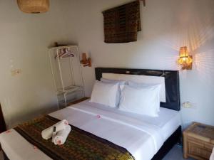 een slaapkamer met een bed met witte lakens en kussens bij Jepun homestay, gerupuk, pujut, lombok in Bumbang
