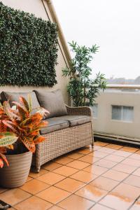 um sofá de vime sentado num pátio com plantas em Lakeside 3-Bed Apartment with Jacuzzi em Belconnen