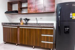 a kitchen with a black refrigerator and wooden cabinets at Cómodos apartamentos cerca al metro de Medellín in Medellín