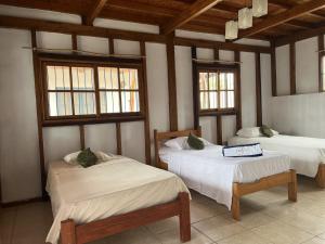 een kamer met 2 bedden en 2 ramen bij Sand Castle Ocean Suites in Zorritos