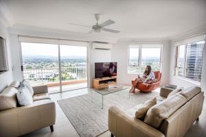 a woman sitting in a living room with a tv at Belle Maison Apartments - Official in Gold Coast