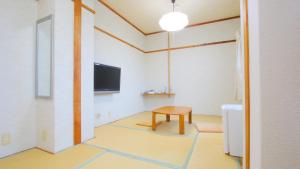 a room with a table and a tv on a wall at Business Hotel Furusato in Ibusuki