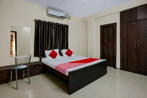 a bedroom with a bed with red pillows and a chair at A S Hotels Ranchi in Rānchī