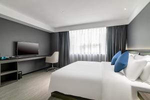 a bedroom with a large white bed with blue pillows at Insail Hotels (Guangyuanxincun Jingtai Pedestrian Street Guangzhou) in Guangzhou