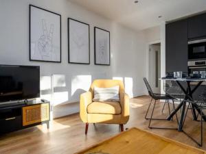 uma sala de estar com uma cadeira amarela e uma televisão em Pass the Keys Modern and Bright Home Minutes From Central London em Londres