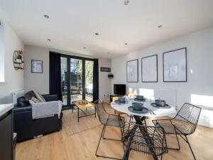 uma sala de estar com uma mesa e cadeiras e um sofá em Pass the Keys Modern and Bright Home Minutes From Central London em Londres
