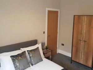 a bedroom with a bed and a wooden cabinet at Pass the Keys Superb 1st Floor Town Centre Apartment Refurbished in Grimsby