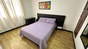 ein Schlafzimmer mit einem Bett mit einer lila Bettdecke in der Unterkunft Hermoso loft a una cuadra del parque principal in Líbano