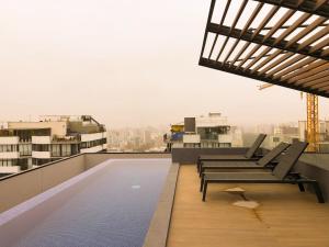 un balcone con sedie e una piscina in un edificio di Apartamento exclusivo a 70 metros de san Isidro a Lima