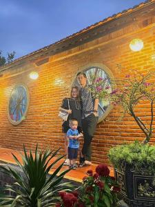 a man and a woman and a child standing in front of a brick building at Home of bong & gao in B'su M'rac