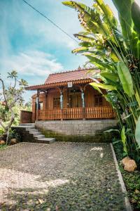 a wooden house with a stone walkway in front of it at Umadhatu Resort by Amerta in Tabanan