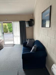 un soggiorno con divano blu e TV di Helensborough Motor Inn a Balclutha