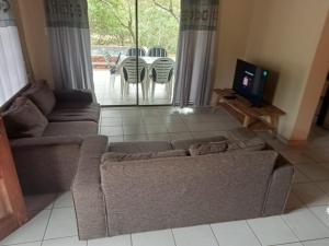 a living room with a couch and a tv at Le Lion Dort in Marloth Park