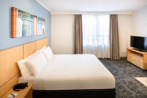 a hotel room with a bed and a television at Mercure Brisbane Garden City in Brisbane