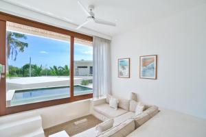 a living room with a couch and a large window at Pagi Villas by Hombali in Mengwi