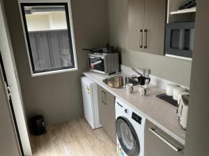 a small kitchen with a sink and a washing machine at Pegasus Amberley, Entire Studio in Waikuku