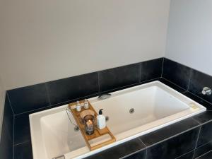 a large white tub in a bathroom with black tiles at Pegasus Amberley, Entire Studio in Waikuku