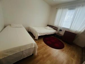 een slaapkamer met 2 bedden, een raam en een tapijt bij Whole Apartment in Vantaa