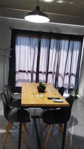 a wooden table with black chairs in a room at Don Will Aparts in Puerto Esperanza