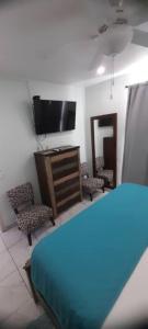a bedroom with a bed and a tv and chairs at Cozyhideaway in Providenciales
