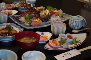 a table with plates of food and bowls of soup at あじ彩の宿小浜荘 in Toba