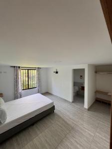 a large white bedroom with a bed and a window at Habitación con Baño Privado en Casa Campestre in Sabaneta