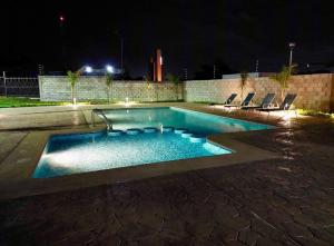 a swimming pool at night with chairs around it at E&S Estancia vacacional in Mazatlán