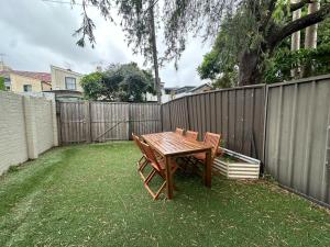 a wooden table and chairs next to a fence at Dynamic 2 Bedroom home close to city buzz Darling St 2 E-Bikes Included in Sydney
