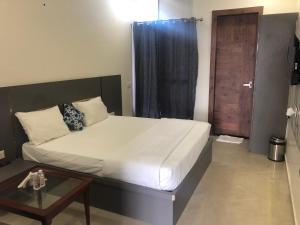 1 dormitorio con cama, mesa y puerta en C T Heights Inn en Bharatpur