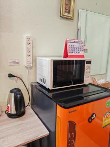 a microwave oven sitting on top of a refrigerator at The Backpacker stn in Nonthaburi