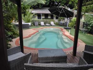 a swimming pool with chairs and an umbrella at Coach House Inn in Bright