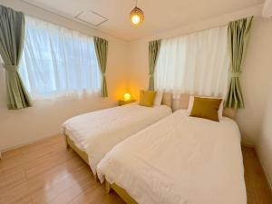 - une chambre avec 2 lits et une fenêtre dans l'établissement グランディオーソ沖縄ヴィラ恩納1, à Onna
