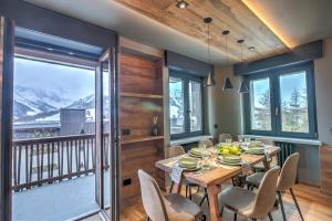 ein Esszimmer mit einem Tisch und Stühlen sowie einem Balkon in der Unterkunft Simona LuxuryApartment Few Steps From Ski - Happy Rentals in Sestriere