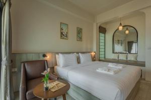 een slaapkamer met een groot wit bed en een stoel bij Ang Pao Hotel - SHA Extra Plus in Phuket