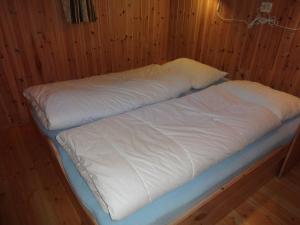ガイランゲルにあるMaråk Hytteutleigeの白いシーツが備わる木造の部屋のベッド1台
