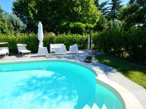 a swimming pool in a yard with chairs and a umbrella at Pretty villa in Marsciano with nice garden and private pool in Marsciano