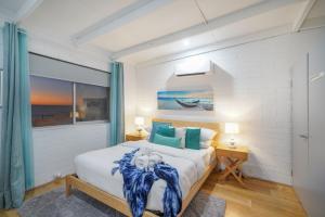 a bedroom with a king sized bed with blue accents at OCEA84 - Quinns Beach Shack: Ocean Views in Quinns Rocks