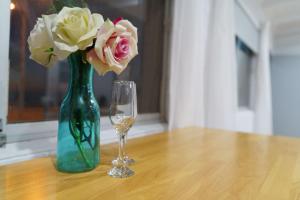 a green vase with flowers and a glass at OCEA84 - Quinns Beach Shack: Ocean Views in Quinns Rocks