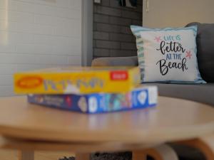 a stack of books on a coffee table with a pillow at OCEA84 - Quinns Beach Shack: Ocean Views in Quinns Rocks