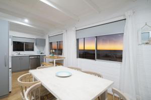 a kitchen and dining room with a white table and chairs at OCEA84 - Quinns Beach Shack: Ocean Views in Quinns Rocks