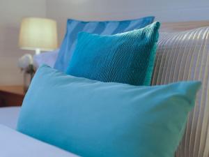 a group of blue pillows on a bed at OCEA84 - Quinns Beach Shack: Ocean Views in Quinns Rocks