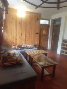 a room with two tables and benches in it at manorma cottage in Dharamshala