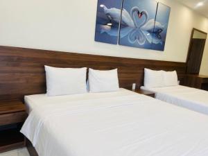two beds in a hotel room with white sheets at MARINA Bình Dương in Ấp Phú Thọ
