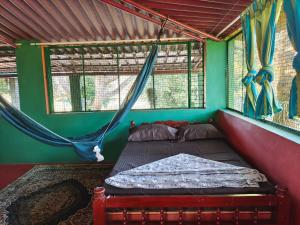 a bed in a room with green walls and windows at Ranjo's Farm house in Chāmrājnagar