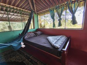 a bed with a hammock in a room with windows at Ranjo's Farm house in Chāmrājnagar