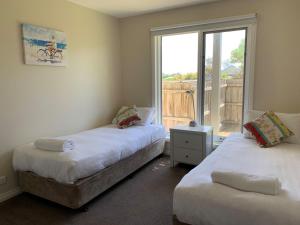 a bedroom with two beds and a window with a balcony at Blue Vista in Port Fairy