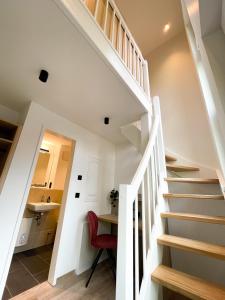 a white staircase in a house with a red chair at HOLI City Apart Hotel Berlin in Berlin