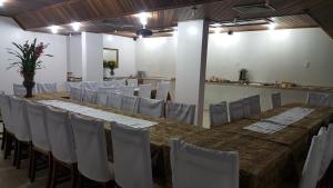 a conference room with a long table and white chairs at Cristal Executive Hotel in Francisco Beltrão